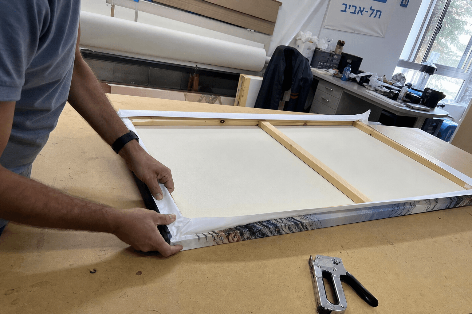 מתיחת קנבס כותנה בקפידה על מסגרת עץ בסטודיו